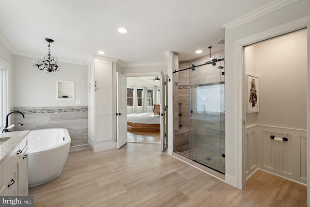 full bathroom with vanity, a freestanding tub, a shower stall, wainscoting, and crown molding