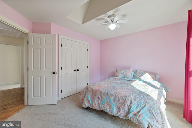 carpeted bedroom featuring a closet, baseboards, attic access, and a ceiling fan