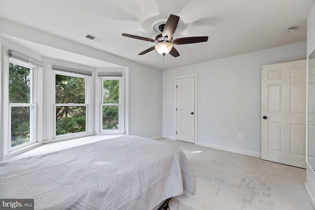 bedroom with visible vents, light colored carpet, baseboards, and ceiling fan