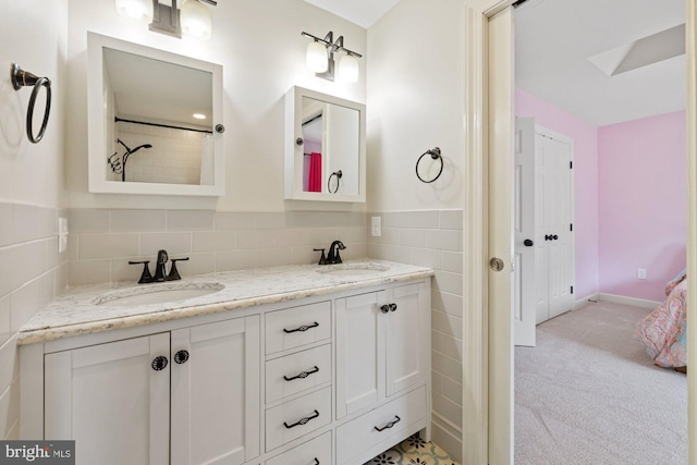 full bathroom featuring a sink, tile walls, wainscoting, and double vanity