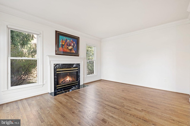 unfurnished living room featuring wood finished floors, a high end fireplace, and ornamental molding