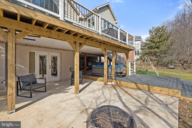 view of patio / terrace featuring stairway, a wooden deck, an outdoor fire pit, a hot tub, and french doors