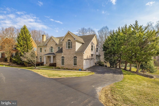 view of front facade with driveway, brick siding, an attached garage, and a front lawn