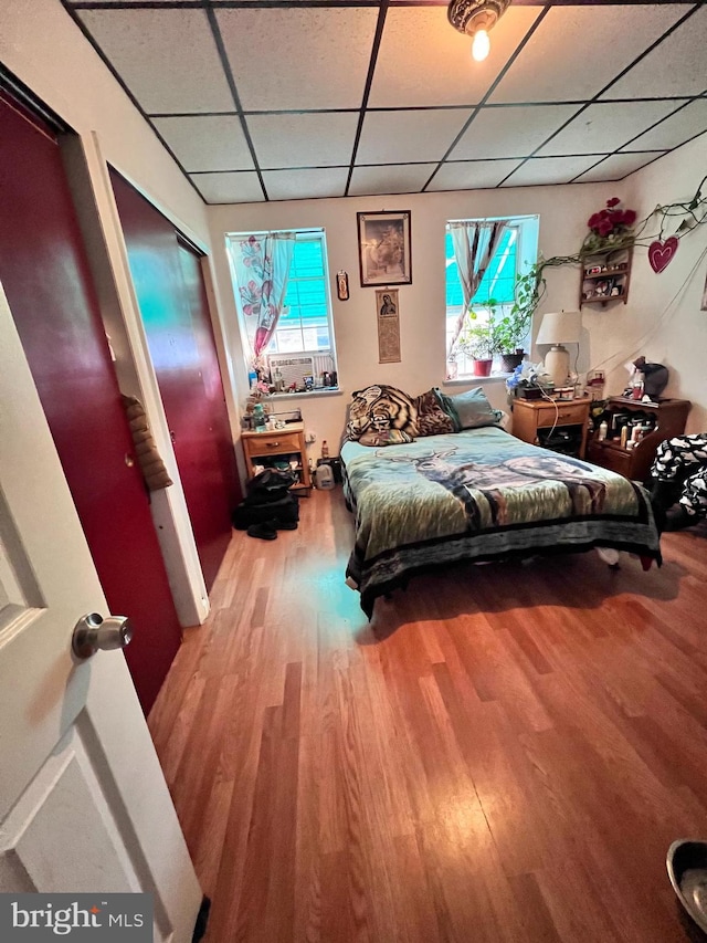 bedroom with a drop ceiling and wood finished floors