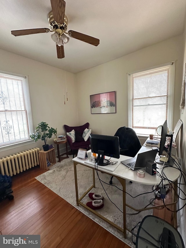 office area with radiator heating unit, a ceiling fan, and wood finished floors