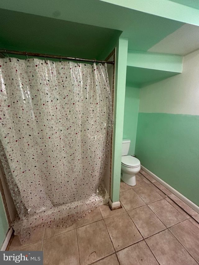 full bathroom featuring toilet, a shower with curtain, tile patterned flooring, and baseboards