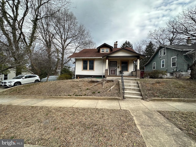 bungalow-style home featuring covered porch and a chimney