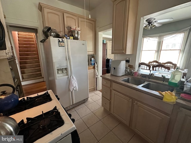 kitchen featuring light tile patterned floors, white appliances, a sink, a ceiling fan, and light countertops