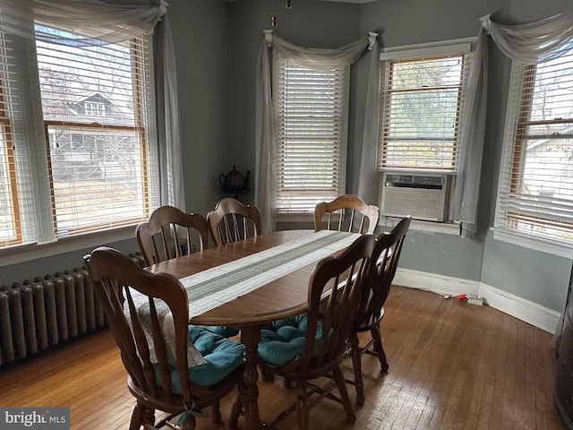 dining space with cooling unit, baseboards, radiator heating unit, and hardwood / wood-style flooring