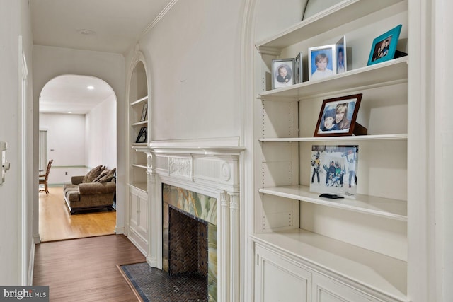 hall with arched walkways, dark wood finished floors, built in features, and recessed lighting