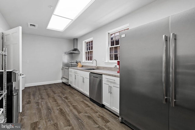 kitchen featuring a sink, visible vents, appliances with stainless steel finishes, wall chimney range hood, and dark wood-style floors