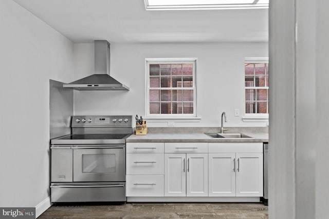 kitchen with electric range, white cabinetry, a sink, wall chimney range hood, and wood finished floors