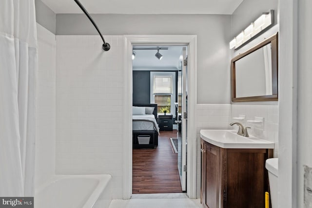 bathroom with tile walls, toilet, shower / bath combo, wainscoting, and vanity