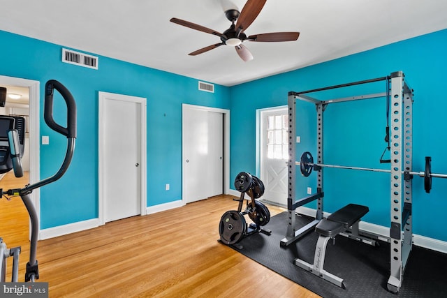 workout area with a ceiling fan, wood finished floors, visible vents, and baseboards