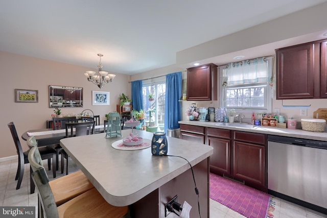 kitchen featuring a sink, light countertops, stainless steel dishwasher, a notable chandelier, and a center island