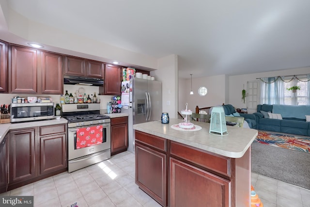 kitchen featuring stainless steel appliances, light countertops, under cabinet range hood, open floor plan, and reddish brown cabinets