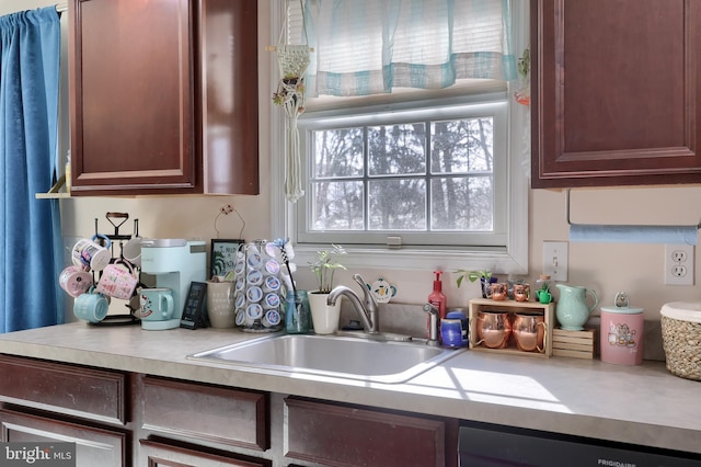 kitchen featuring dark brown cabinets, dishwasher, light countertops, and a sink