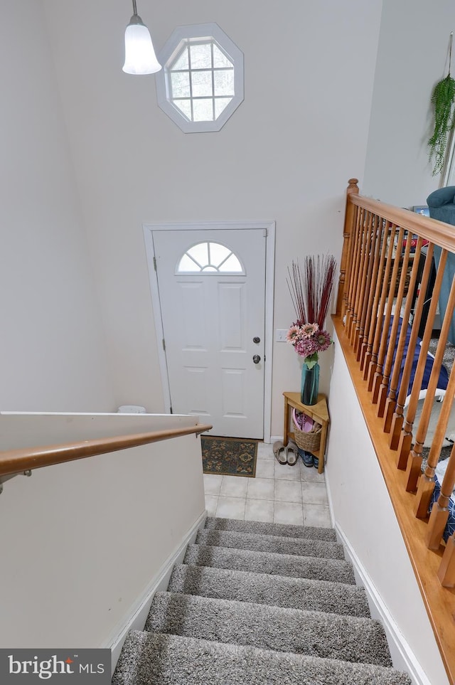 staircase with tile patterned floors, baseboards, and a towering ceiling