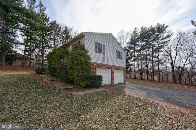 view of property exterior featuring aphalt driveway, a garage, and brick siding