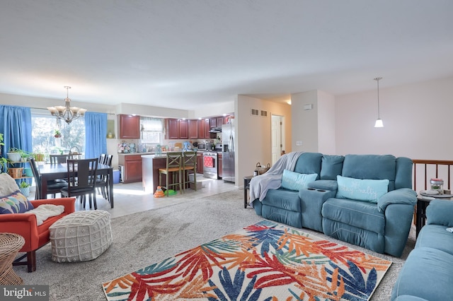 living room with light carpet, visible vents, and an inviting chandelier