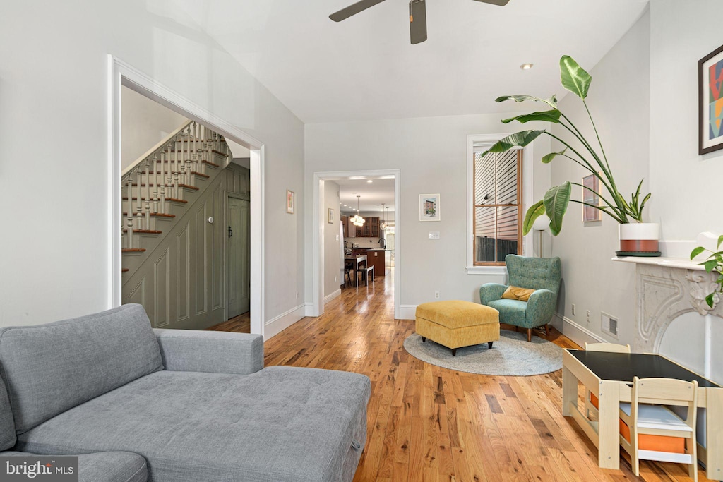 living area with ceiling fan, stairway, wood finished floors, and baseboards