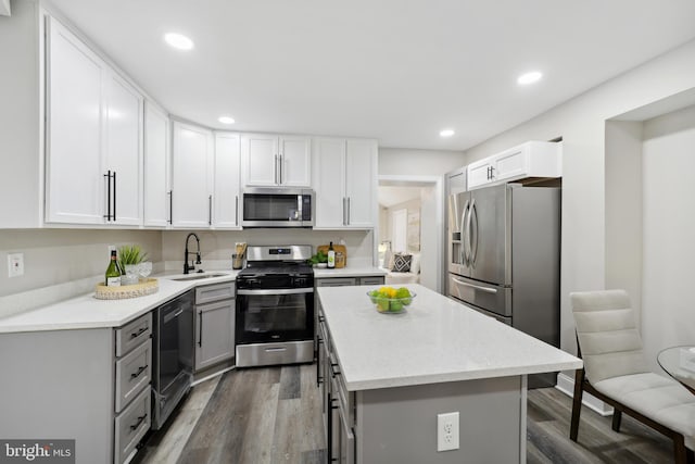 kitchen with dark wood-style floors, a kitchen island, stainless steel appliances, gray cabinetry, and a sink