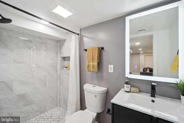 full bathroom with toilet, visible vents, a tile shower, and vanity