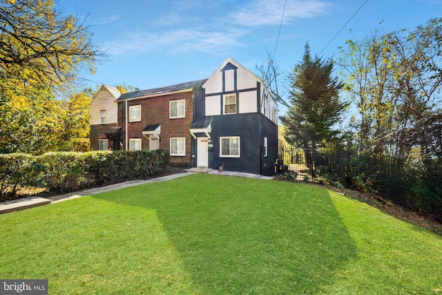 view of front of property featuring a front lawn, fence, brick siding, and stucco siding