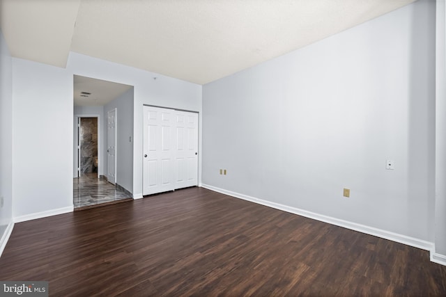 empty room featuring dark wood-style flooring and baseboards