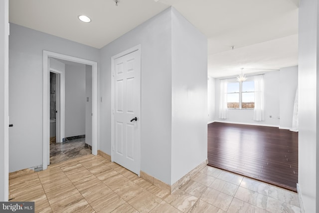 unfurnished room featuring baseboards and an inviting chandelier