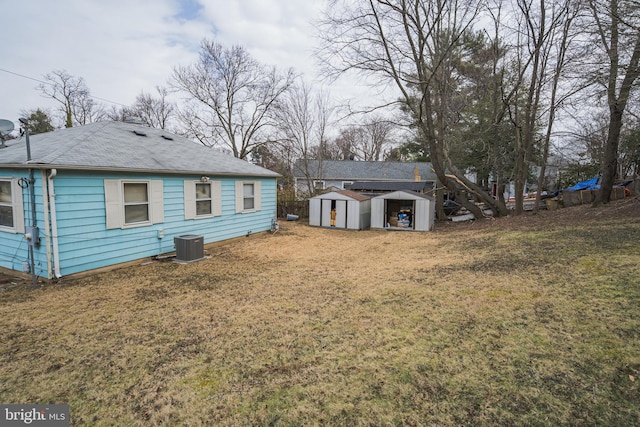 rear view of house featuring a storage shed, central AC, a lawn, and an outbuilding