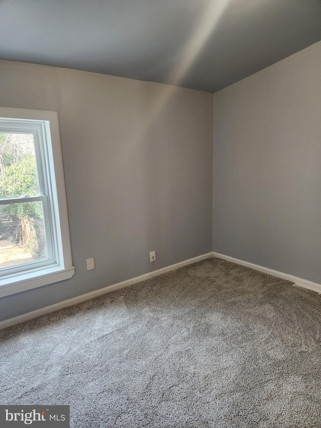 carpeted spare room featuring baseboards