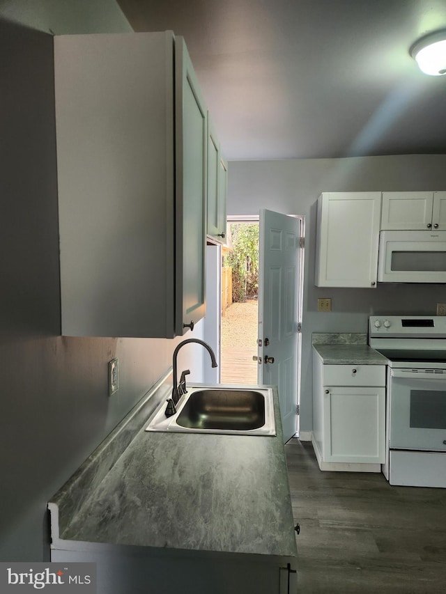 kitchen with white appliances, dark wood-style floors, white cabinets, and a sink