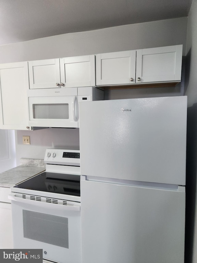 kitchen featuring light countertops, white appliances, and white cabinets