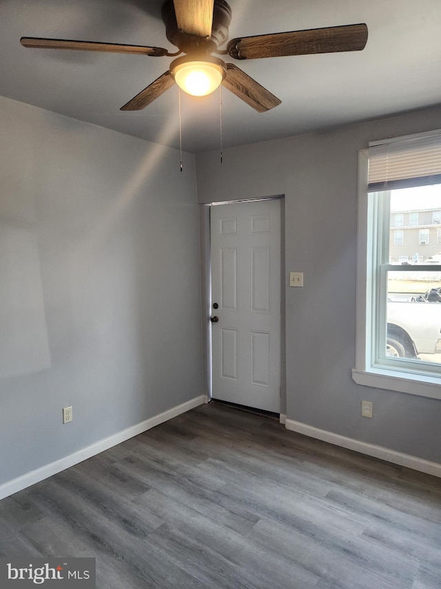 spare room with dark wood-type flooring, baseboards, and a ceiling fan