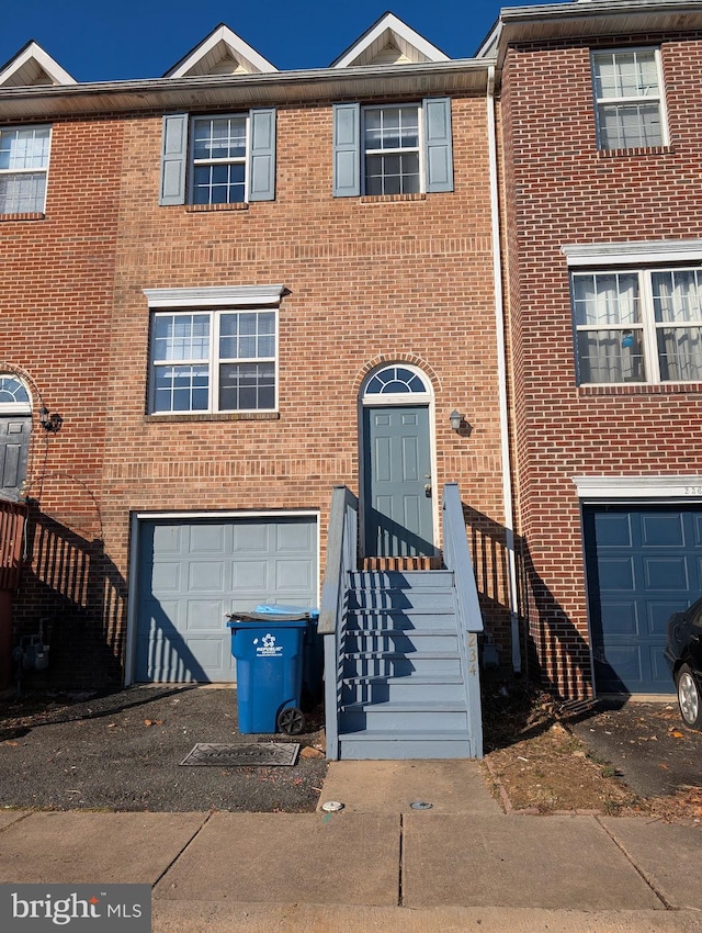 view of property with an attached garage, entry steps, and brick siding