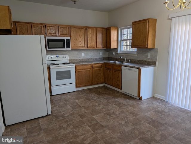 kitchen featuring white appliances, tasteful backsplash, brown cabinetry, dark countertops, and a sink