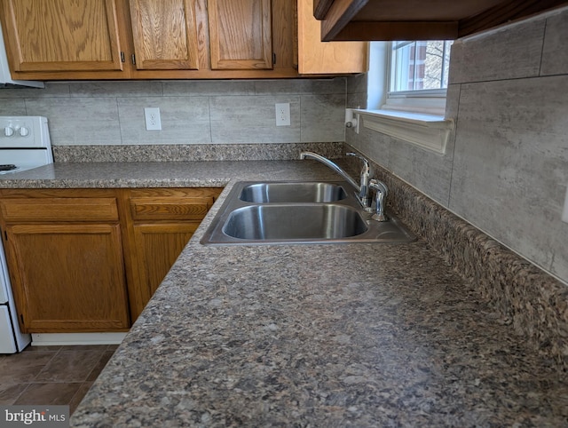 kitchen with brown cabinetry, electric stove, a sink, and decorative backsplash