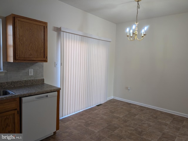 kitchen featuring white dishwasher, a notable chandelier, backsplash, brown cabinetry, and dark countertops