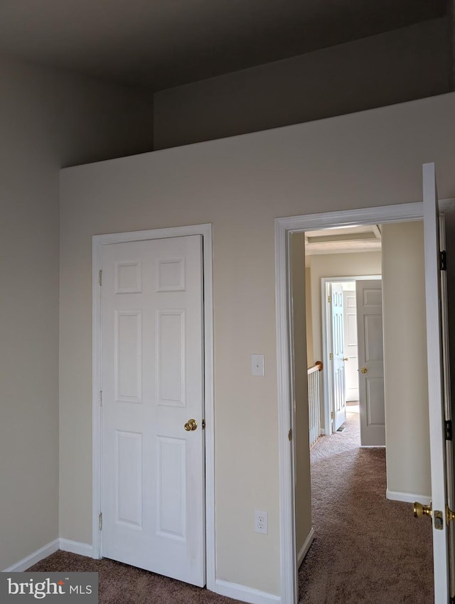 hallway with baseboards and dark carpet