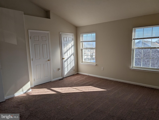 carpeted spare room featuring baseboards and vaulted ceiling