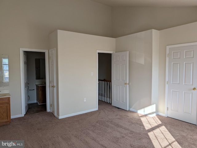 unfurnished bedroom with carpet, high vaulted ceiling, and baseboards