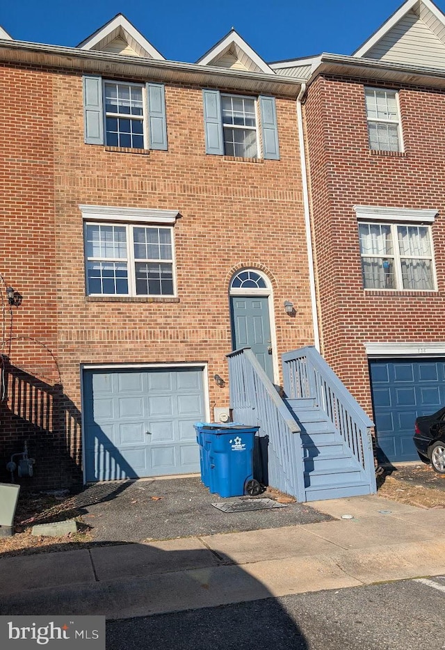 townhome / multi-family property featuring brick siding, driveway, and an attached garage