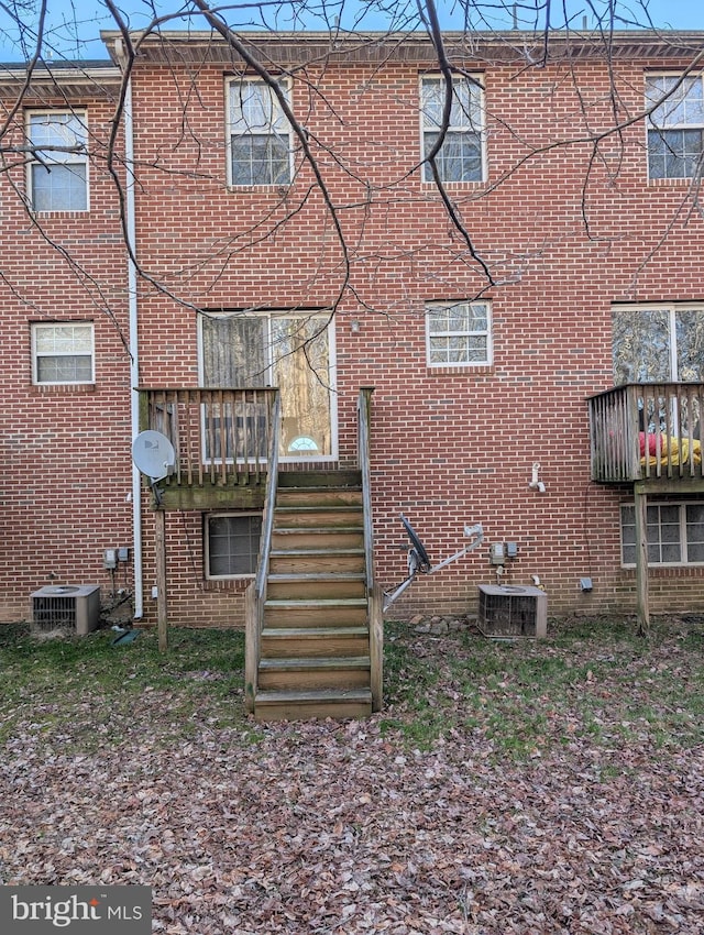 back of house featuring central AC unit and brick siding