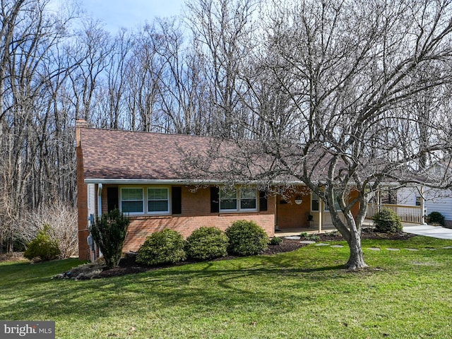 single story home with brick siding, a chimney, and a front yard