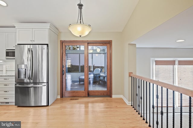 kitchen featuring white cabinets, visible vents, stainless steel fridge, and light wood-type flooring