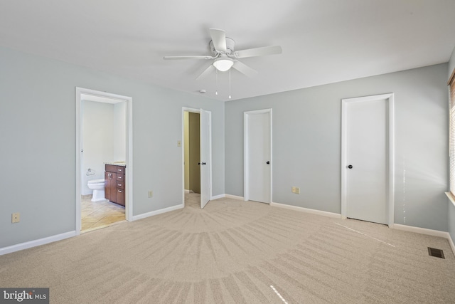 unfurnished bedroom with visible vents, two closets, ensuite bathroom, baseboards, and light colored carpet