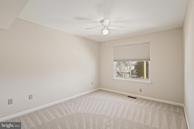 carpeted empty room with visible vents, a ceiling fan, and baseboards