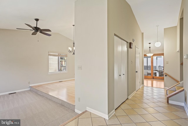 hallway featuring lofted ceiling, light tile patterned floors, visible vents, and baseboards