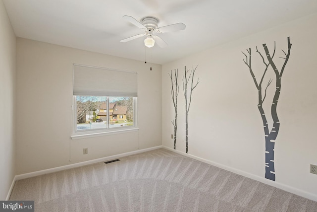 empty room with baseboards, visible vents, carpet floors, and ceiling fan